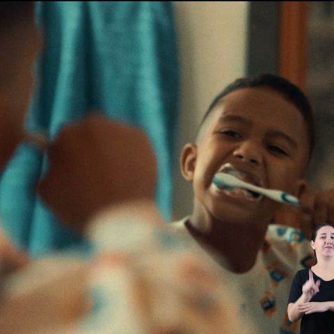 Garoto escovando os dentes em frente ao espelho